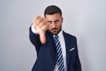 Wall Mural - Handsome hispanic man wearing suit and tie looking unhappy and angry showing rejection and negative with thumbs down gesture. bad expression.