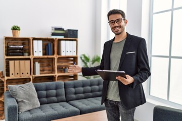 Poster - Young hispanic man having psychology session holding checklist welcoming patient at clinic