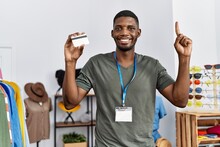 Young African American Man Working As Manager At Retail Boutique Holding Credit Card Smiling With An Idea Or Question Pointing Finger With Happy Face, Number One