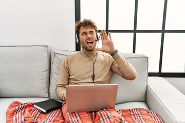 Sticker - Young handsome man with beard wearing operator headset working from home shouting and screaming loud to side with hand on mouth. communication concept.