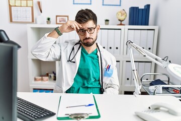 Sticker - Young man with beard wearing doctor uniform and stethoscope at the clinic worried and stressed about a problem with hand on forehead, nervous and anxious for crisis