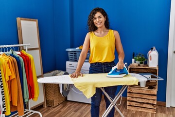 Sticker - Young latin woman smiling confident ironing clothes at laundry room
