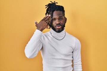 Wall Mural - African man with dreadlocks wearing turtleneck sweater over yellow background shooting and killing oneself pointing hand and fingers to head like gun, suicide gesture.