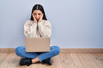 Poster - Young woman using laptop sitting on the floor at home tired hands covering face, depression and sadness, upset and irritated for problem