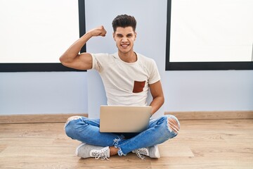 Canvas Print - Young hispanic man using laptop at home strong person showing arm muscle, confident and proud of power