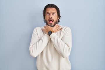 Poster - Handsome middle age man wearing casual sweater over blue background shouting and suffocate because painful strangle. health problem. asphyxiate and suicide concept.