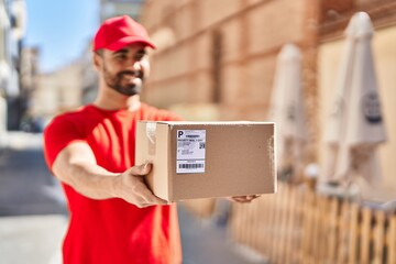 Canvas Print - Young hispanic man courier holding package at street