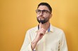 © Krakenimages.com - Hispanic young man wearing business clothes and glasses thinking concentrated about doubt with finger on chin and looking up wondering