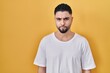 © Krakenimages.com - Young handsome man wearing casual t shirt over yellow background skeptic and nervous, frowning upset because of problem. negative person.