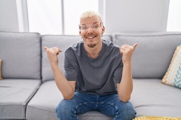 Sticker - Young caucasian man wearing virtual reality glasses looking confident with smile on face, pointing oneself with fingers proud and happy.