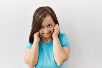 Canvas Print - Young down syndrome woman standing over isolated background covering ears with fingers with annoyed expression for the noise of loud music. deaf concept.