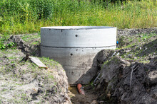 Concrete Septic Tank Made Of Several Rings With An Orange Drainpipe At The Bottom.