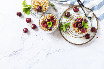 Poster - Healthy menu concept. Home made granola breakfast. Glass of parfait made of granola, berries cherry, yogurt with chia seeds on rustic table. View from above. Copy space.