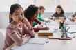 © Prostock-studio - Sad Asian Schoolgirl Looking At Camera Sitting In Modern Classroom