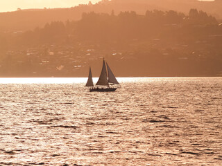 Wall Mural - Silhouette distant hills and yacht sailing in under red sky at sunset