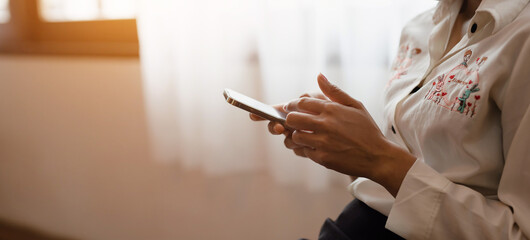 Close-up of a woman's hand using a mobile phone at home. Search ideas or social networks.
