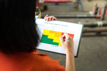 Wall Mural - action of a manager is using ballpoint pen to evaluate on risk assessment matrix of the project inve