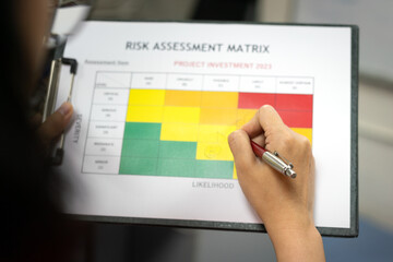 Wall Mural - action of a manager is using ballpoint pen to evaluate on risk assessment matrix of the project inve