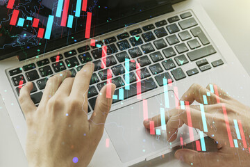 Creative abstract economic crisis chart with world map hologram and with hands typing on computer keyboard on background, bankruptcy and recession concept. Multiexposure