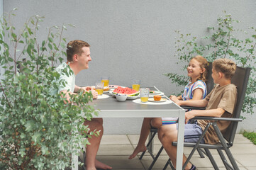 Wall Mural - Happy dad with teen children having brunch outdoors