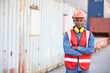 © offsuperphoto - portrait African factory worker or engineer folded arms pose in containers warehouse storage