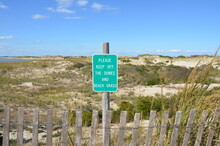 Wood Fence And Sand Dunes At The Beach With Please Keep Off Sign