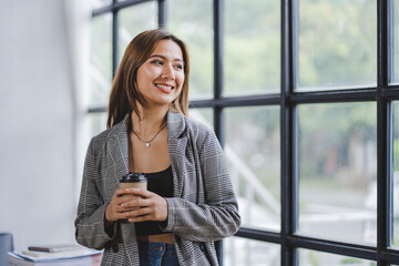 Wall Mural - Portrait of an Asian woman by the window at her office. Portrait of a businessman, employee, online marketing, ecommerce, online marketing concept.