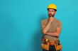 © New Africa - Professional builder in hard hat with tool belt on light blue background, space for text