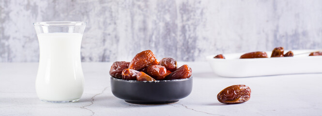 Dates in a bowl and a glass of milk on the table. Food for the holy month of Ramadan. Web banner