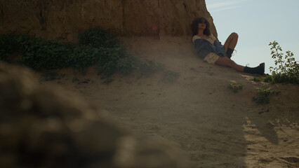 Wall Mural - Carefree girl sitting shadow leaning on hill. Attractive woman relax on sand.