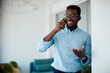 © Drazen - Happy black businessman talking on cell phone in office.