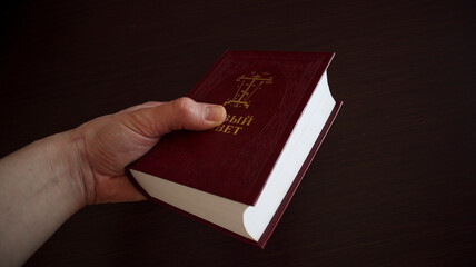 Wall Mural - A man holds and reads the Holy Scriptures a Bible with an inscription in the Old Slavonic language. Saint Bible. gospel. New Testament.