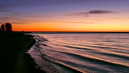 Wall Mural - Delicate waves ripple onto the beach at morning twilight, reflecting amazingly colorful dawn sky.
