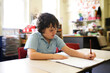 © Austockphoto - girl with short hair sitting and drawing on the drawing pad with pencil in classroom