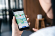 © Kannapat - Hand of young woman searching location in map online on smartphone.