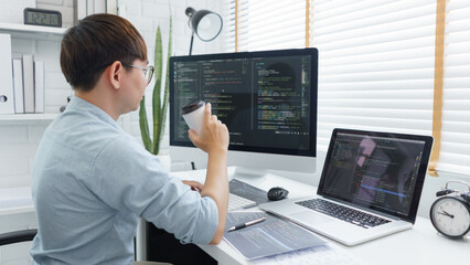 Wall Mural - software development concept, male programmer checking website programming and drinking coffee