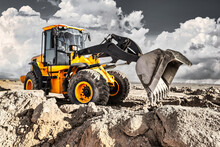 Powerful Bulldozer Or Loader Moves The Earth At The Construction Site Against The Sky. An Earthmoving Machine Is Leveling The Site. Construction Heavy Equipment For Earthworks.