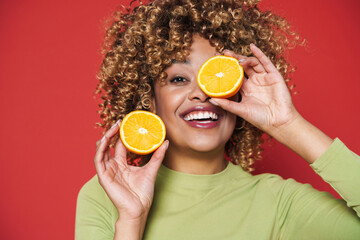 Wall Mural - Young black woman with afro curls having fun holding orange