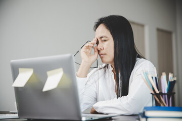 Wall Mural - Young business woman person sleepy and has frustration eye problems with cephalalgia disease from using laptop computer on her office desk. Stressed female employee tired and exhausted from overwork.