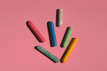 Wall Mural - colored crayons on a pink background in hard light