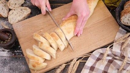 Canvas Print - woman slicing fresh baguette bread on wooden cutting board