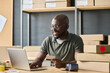 © Mediaphotos - African warehouse worker paying online with credit card typing on laptop at table