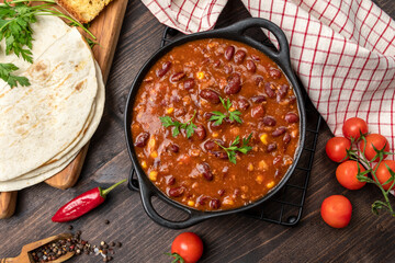 Wall Mural - Mexican food chile con carne dish on a wooden backdrop. Bean and corn soup, red bean stew