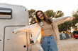 Cheerful young caucasian woman waving her arms enjoys spending time in camping. Brunette smiling looking at camera, wears casual clothes. Lifestyle, different emotions, leisure concept.