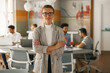 © Kostiantyn - Portrait of smiling businesswoman in suit standing in modern office on colleagues background