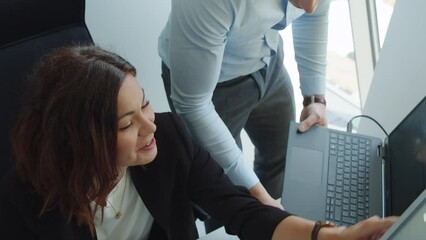Man and woman collaborating on computers in a corporate office environment