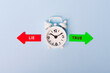 hard vs easy. Red arrow and green arrow- direction indicator - choice of hard or easy. Concept of choice. Two Arrows and White alarm clock on blue background, top view