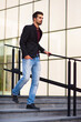 © Solid photos - Young businessman walking on the stairs in front of corporate office building