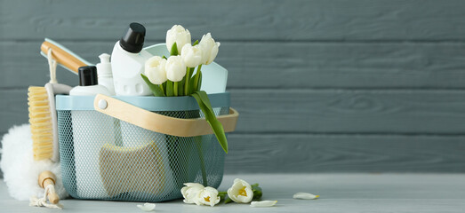 Set of cleaning supplies and spring flowers on grey wooden background