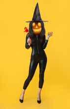 Woman With Carved Pumpkin Instead Of Her Head On Yellow Background. Halloween Celebration